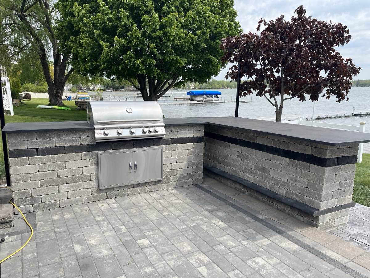 An outdoor kitchen with a bar counter overlooking a lake