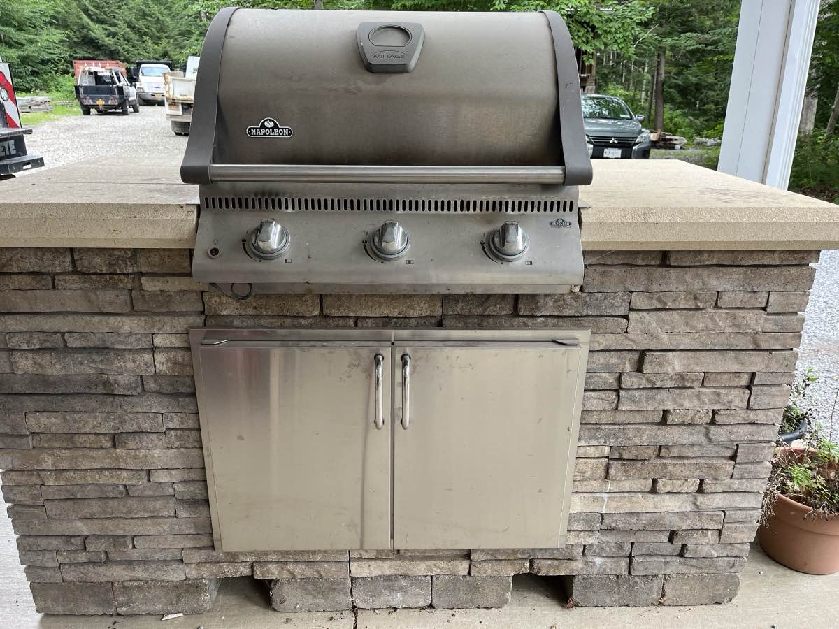 A built-in grill set into a stone outdoor kitchen