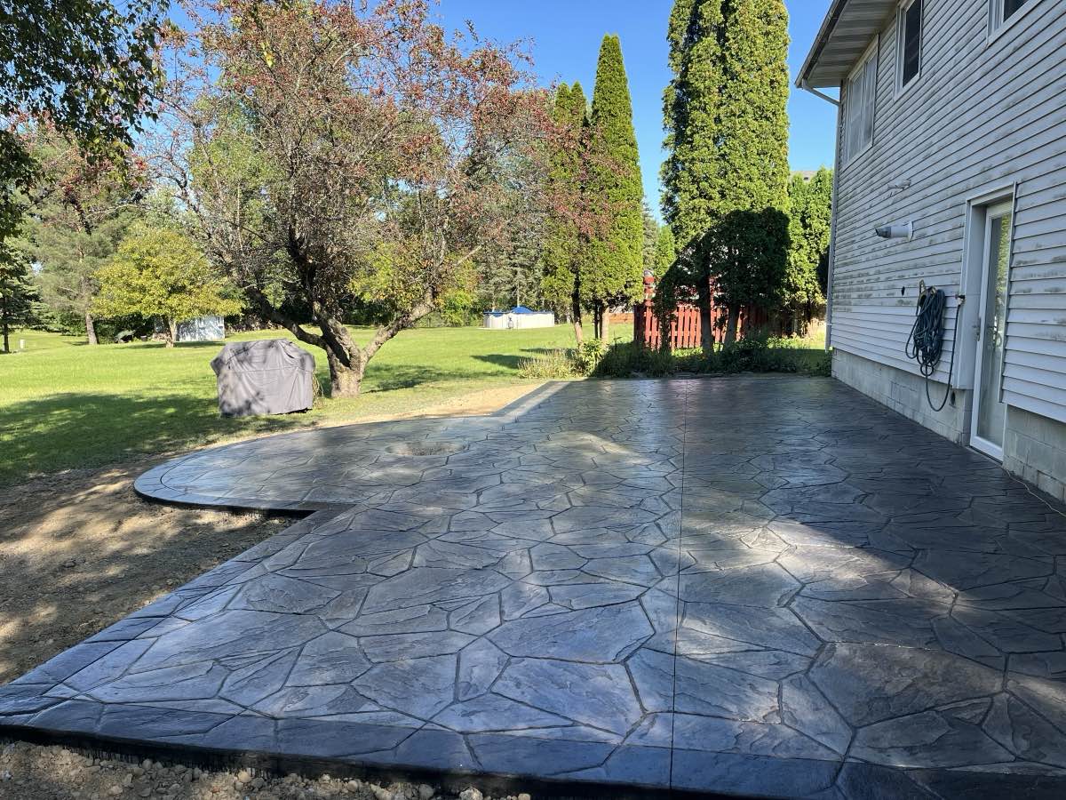 A large stamped concrete patio behind a home