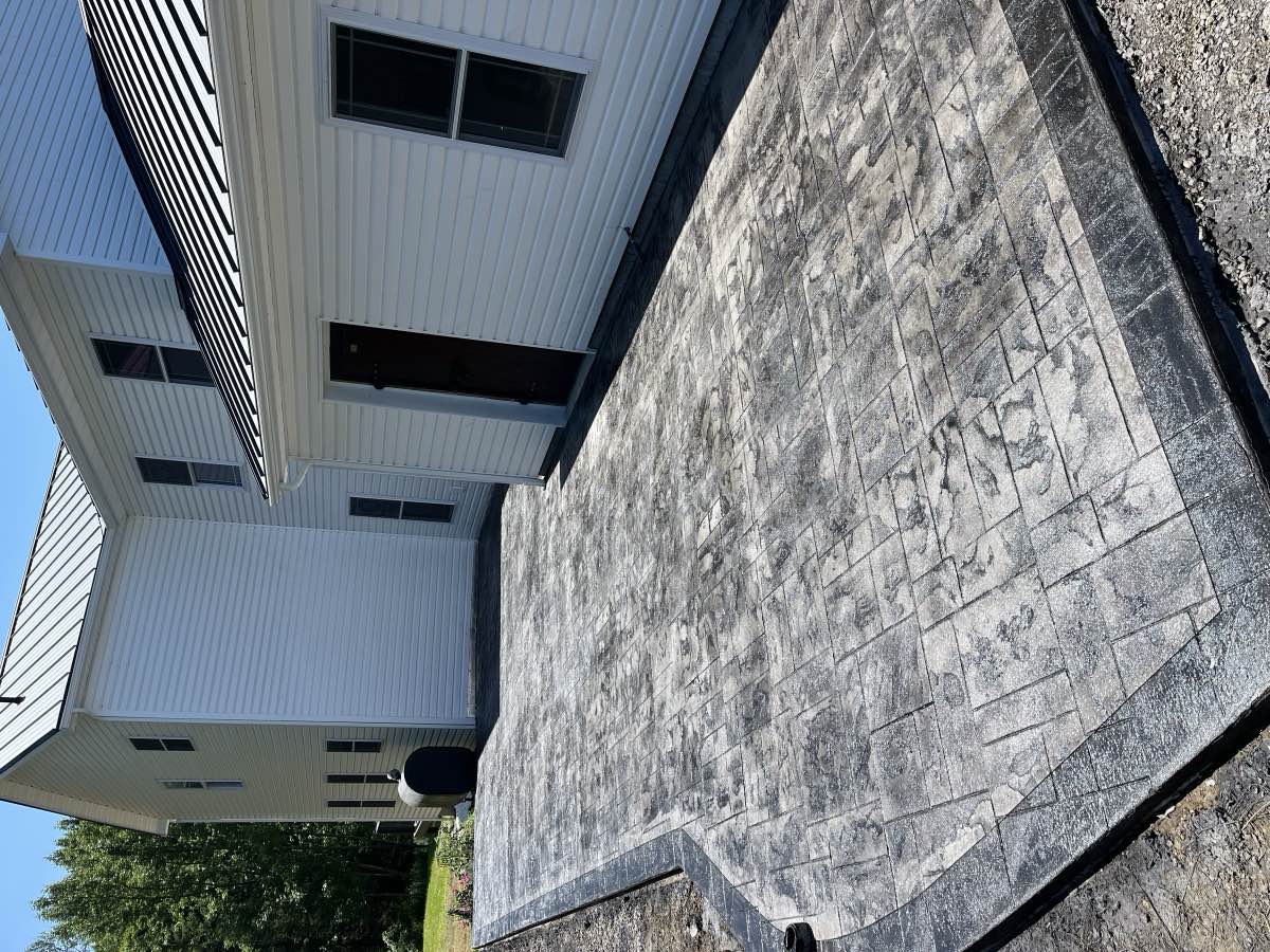 A stamped concrete patio along the side of a house