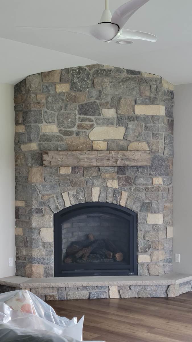 An indoor stone fireplace with a timber mantel